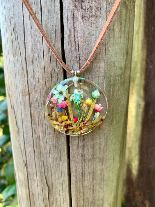 Necklace with a round pendant featuring colourful flowers in resin.